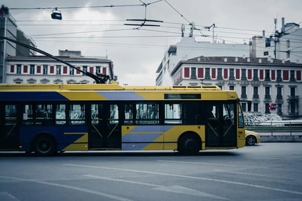 Yellow trolleybus with blue stripe street view exterior