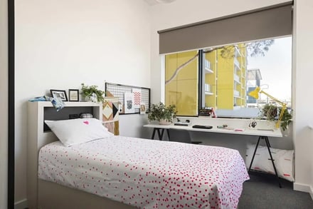 Bed with pink dots desk with yellow lamp bedroom at Campus Perth in Perth Student Accommodation