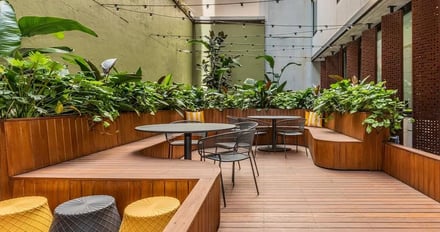 Wooden benches tables chairs and planters outdoor seating area at Iglu Central in Sydney Student Accommodation