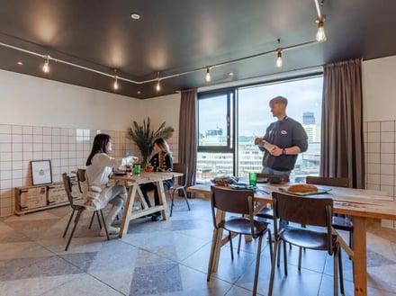 People dining at tables near window common area at True Birmingham in Birmingham Student Accommodation