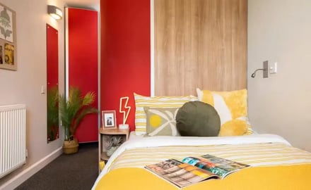 Bed with yellow bedding and pillows bedroom at Emily Bowes Court in London Student Accommodation