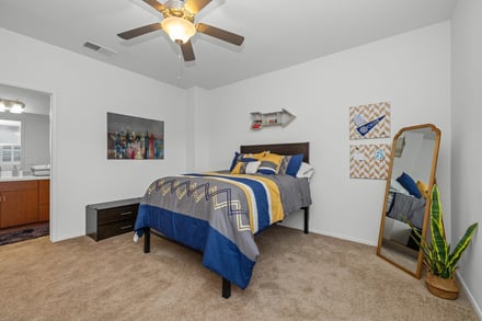 Bed with blue gray yellow bedding fan mirror bedroom at The Glen in San Bernardino Student Accommodation