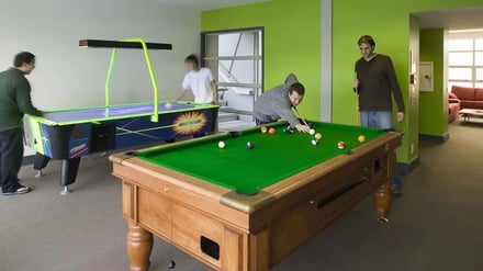 Pool table and air hockey with people playing recreation room at Student Living Auckland in Auckland Student Accommodation