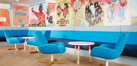 Blue chairs small tables colorful posters common area at Scape Abercrombie in Sydney Student Accommodation