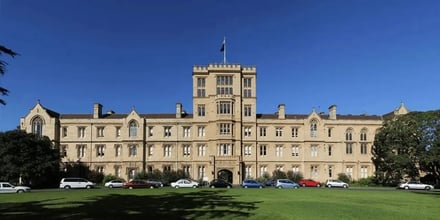 Large sandstone building with cars parked outside exterior at Victoria University Accommodation