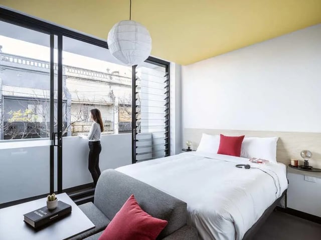 Bed with red pillows and sofa bedroom at UKO Newtown in Sydney Student Accommodation