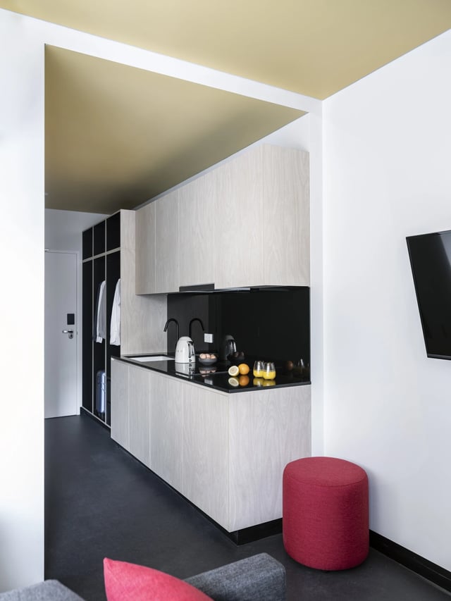 Kitchen with light wood cabinets and red ottoman kitchen at UKO Newtown in Sydney Student Accommodation