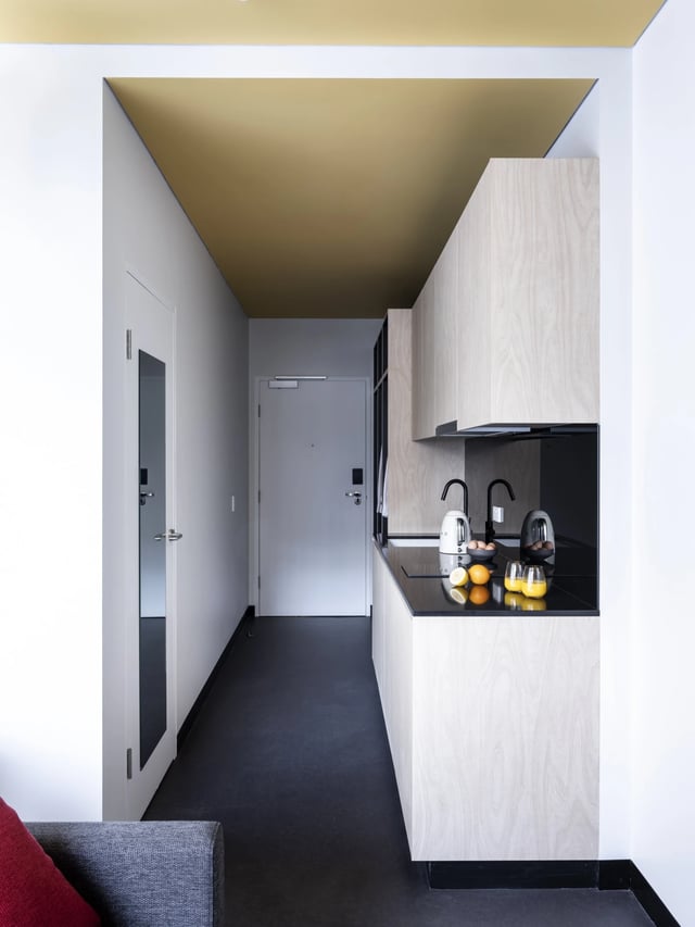 Kitchenette with modern wood cabinets and black countertop kitchen at UKO Newtown in Sydney Student Accommodation