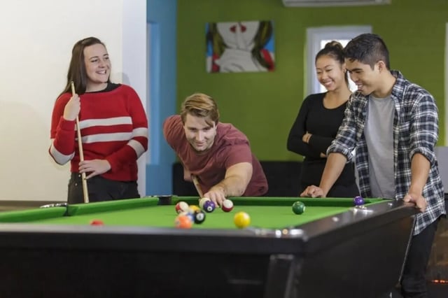 Four students playing pool at a pool table at UNSW Village in Sydney Student Accommodation