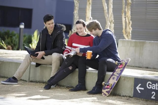 Students sitting outdoors with book and skateboard outdoor area at UNSW Village in Sydney Student Accommodation