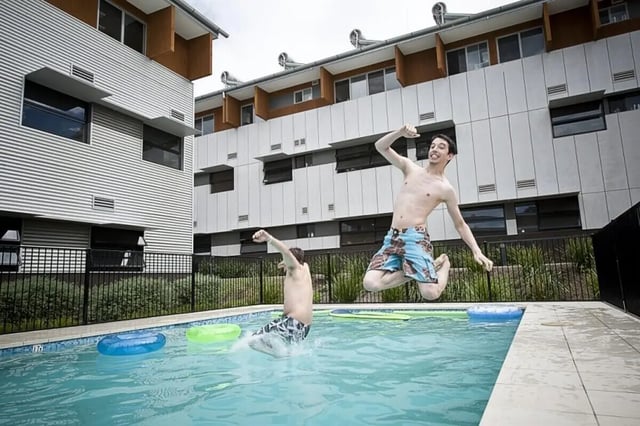 Two students jumping into pool exterior at Western Sydney University Village Parramatta Campus in Sydney Student Accommodation