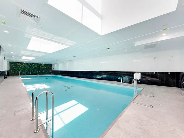Indoor swimming pool with ladders and green wall Playing area at Belong Rosebery in Sydney Student Accommodation