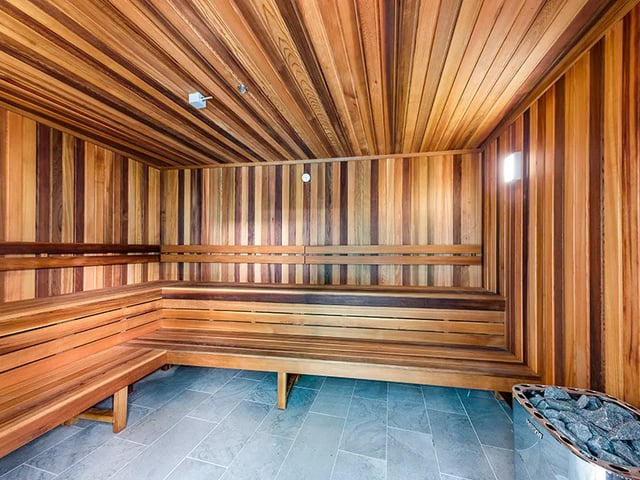 Wooden benches tiled floor sauna with stones at Belong Rosebery in Sydney Student Accommodation