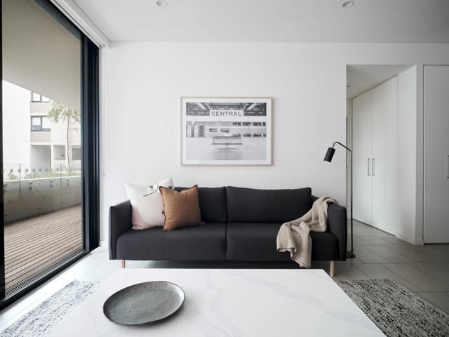 Dark grey sofa with pillows and blanket living room at UKO Camperdown in Sydney Student Accommodation