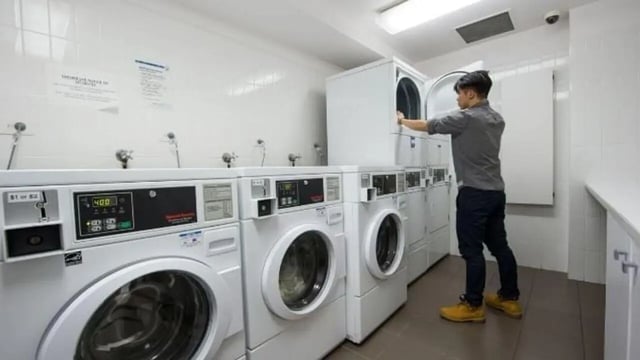 Man using laundry machines washing area laundry room at Student Living D1 in Melbourne Student Accommodation