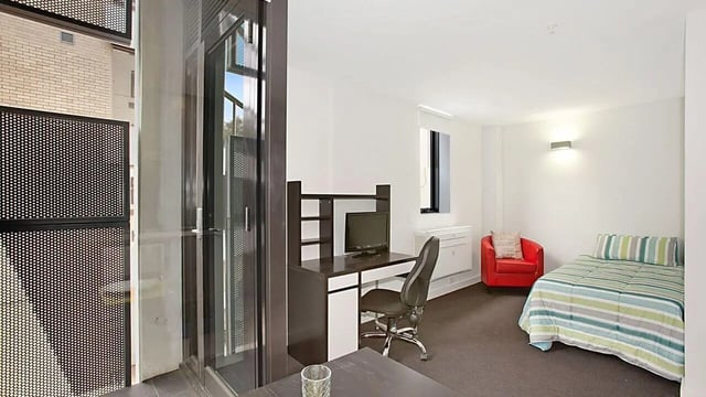 Desk bed red chair and monitor study bedroom at Student Living on Raleigh in Melbourne Student Accommodation
