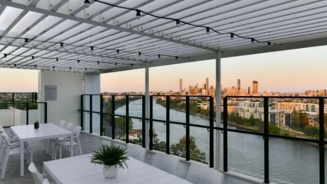 White tables chairs plant city view rooftop area at UniLodge Toowong in Brisbane Student Accommodation