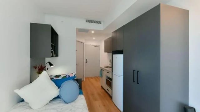 Bed with pillows white fridge and cabinets studio at UniLodge Toowong in Brisbane Student Accommodation