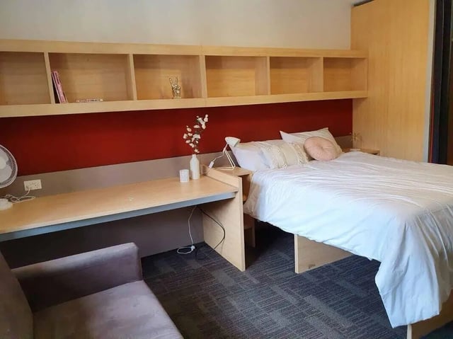 Desk bed fan and shelves bedroom at dwell Village Melbourne City in Melbourne Student Accommodation