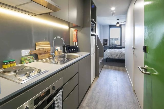 Kitchen with sink stove oven and bedroom study area kitchen at dwell Village Melbourne City in Melbourne Student Accommodation