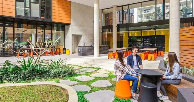 Students chatting at tables and benches outdoor area at Iglu Chatswood in Sydney Student Accommodation