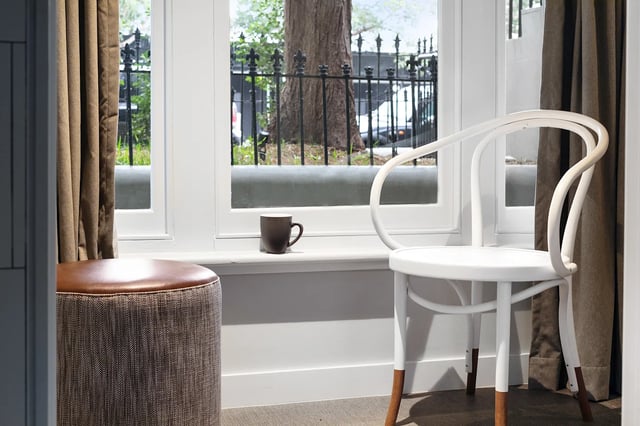 White chair brown ottoman mug window view lounge area at UKO Paddington in Sydney Student Accommodation