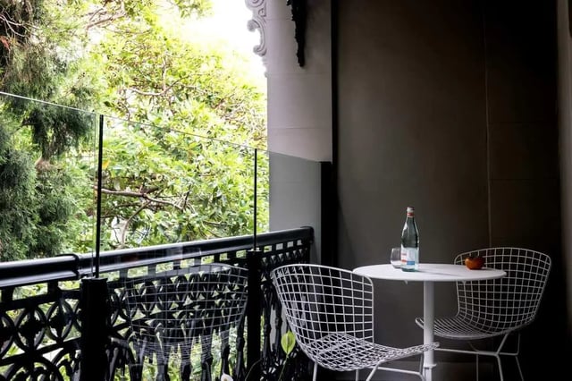White table chairs glass railing lush greenery balcony exterior at UKO Paddington in Sydney Student Accommodation
