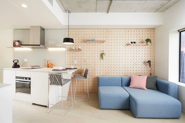 Kitchen with stools and blue sofa living room at Scape Swanston in Melbourne Student Accommodation