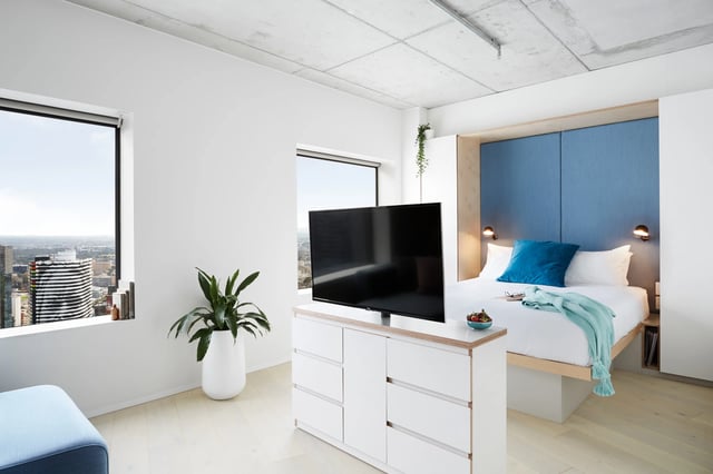 TV dresser bed blue headboard window bedroom at Scape Swanston in Melbourne Student Accommodation
