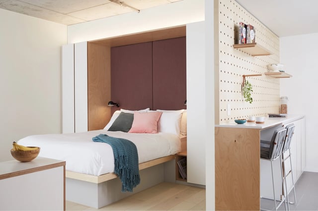Bed with pillows throw blanket and bananas kitchen area bedroom at Scape Swanston in Melbourne Student Accommodation