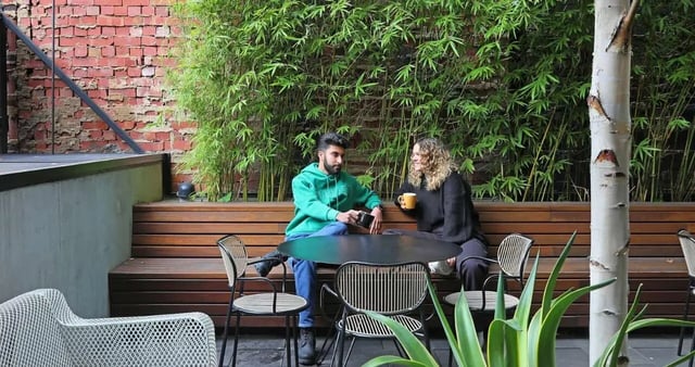 Students sit at a table on wooden bench outdoor area at Iglu Melbourne City in Melbourne Student Accommodation