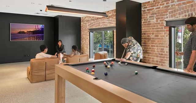 Pool table with people playing living room at Iglu Redfern in Sydney Student Accommodation