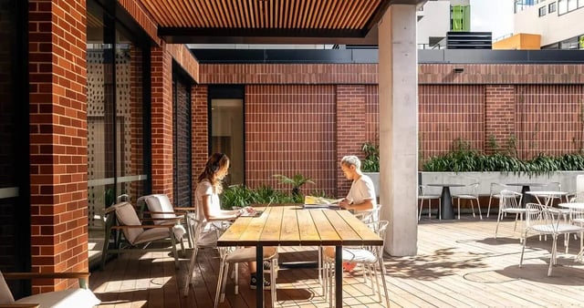 People studying at outdoor wooden table outdoor lounge area at Iglu Redfern in Sydney Student Accommodation