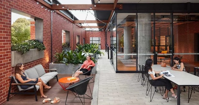 Sofa chairs table plants students outdoor living area at Iglu Redfern in Sydney Student Accommodation