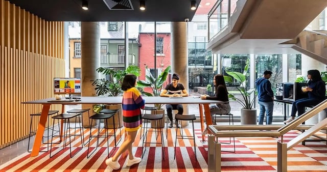 People studying at a long table with stools common area at Iglu Broadway in Sydney Student Accommodation