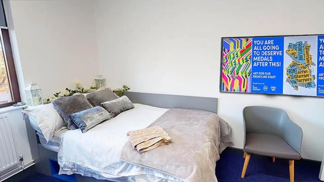 Bed with pillows blanket art and chair bedroom at Oxley Residence in Leeds Student Accommodation