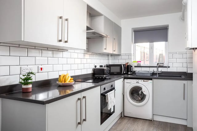 Kitchen with white cabinets toaster microwave and washing machine kitchen at Thornville Court Leeds in Leeds Student Accommodation