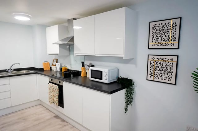 Modern kitchen with white cabinets microwave and artwork Kitchen at Madison Gardens in Nottingham Student Accommodation