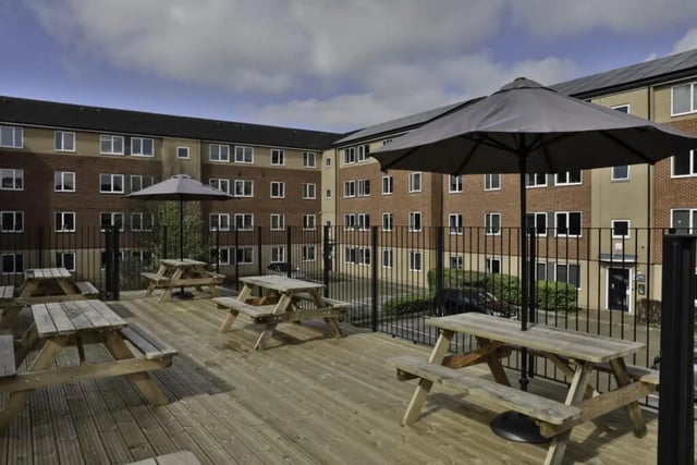 Wooden picnic tables with umbrellas outdoor area exterior at Madison Gardens in Nottingham Student Accommodation