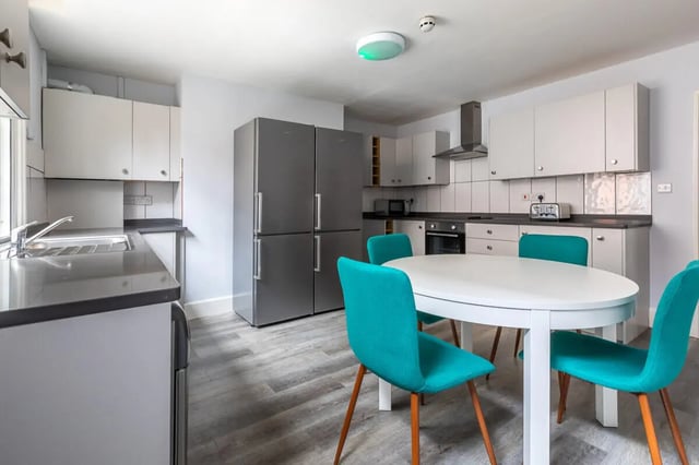 Kitchen with white table turquoise chairs and refrigerators kitchen at Standard Hill in Nottingham Student Accommodation