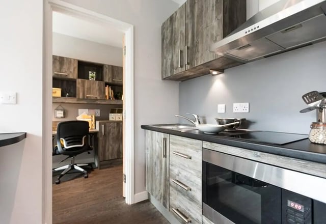 Kitchen with cabinets microwave sink stove and study area. at Queens Court in Reading Student Accommodation
