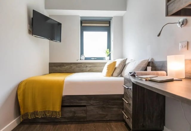 Bed with yellow throw and desk Bedroom at Queens Court in Reading Student Accommodation
