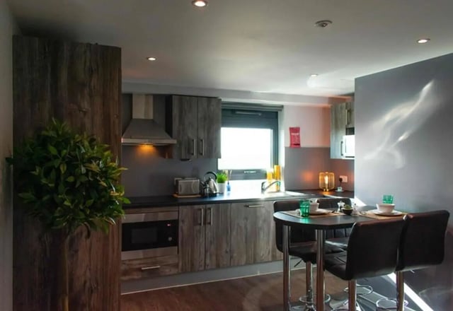 Wooden cabinets microwave sink and dining table kitchen at Queens Court in Reading Student Accommodation