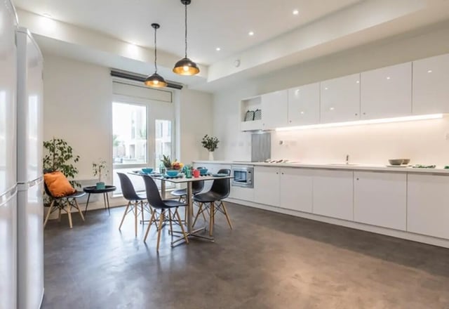 White cabinets dining table with chairs kitchen. at The Cam Foundry in Cambridge Student Accommodation