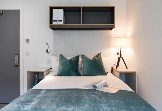 Bed with green pillows and bedside tables bedroom at The Cam Foundry in Cambridge Student Accommodation