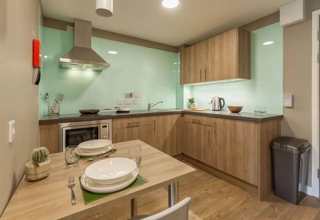 Kitchen with dining table and wooden cabinets kitchen at The Combworks in Aberdeen Student Accommodation