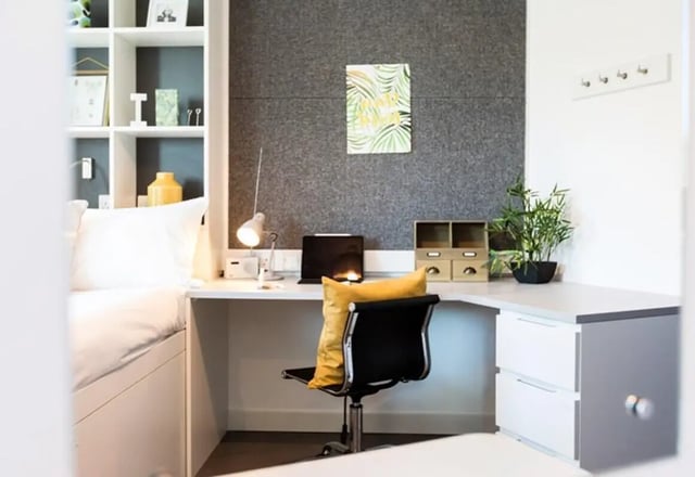 Bed desk chair shelves with books and artwork bedroom at Vogue Studios in Brighton Student Accommodation