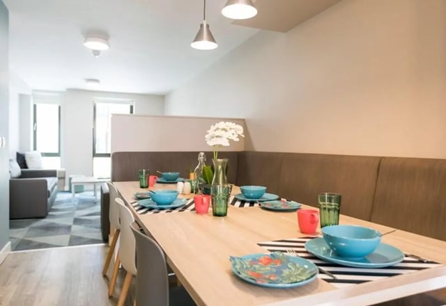 Dining table set with blue plates and sofas living room at Caton Court in Lancaster Student Accommodation