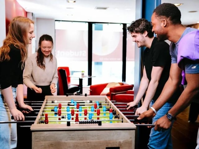 Four students playing foosball in common area. at Bauhaus Student Langstane Place in Aberdeen Student Accommodation