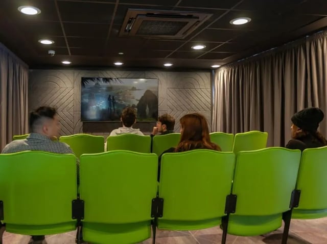 Green seats facing a screen in a cinema room at True Glasgow in Glasgow Student Accommodation